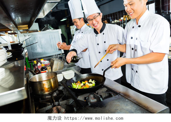 亚洲餐厅厨房做饭和整理菜的高兴的厨师厨师团队在厨房工作